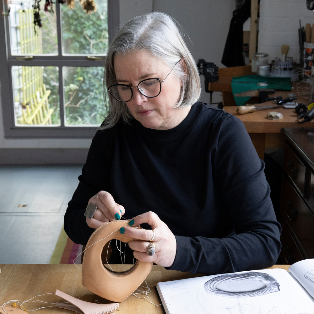 Jewellery Heather Blake sewing one of her Tiamat Collection in her jewellery workshop.