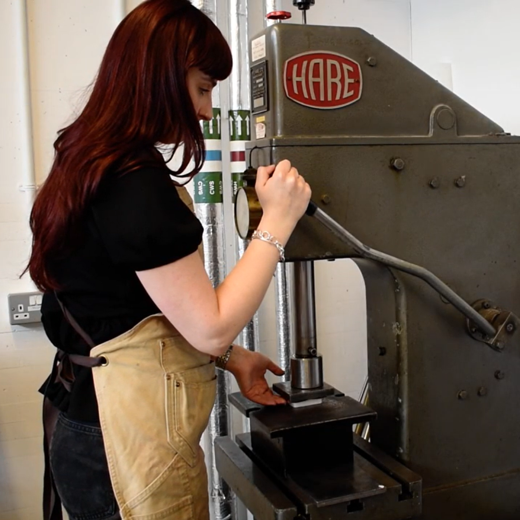 Jeweller Misha McClean operating a press to create her Repeat Prescription Collection 