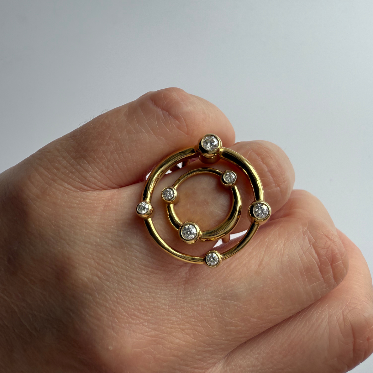 Gold COSMOS cocktail ring by Marina Skia worn on the hand against a plain background