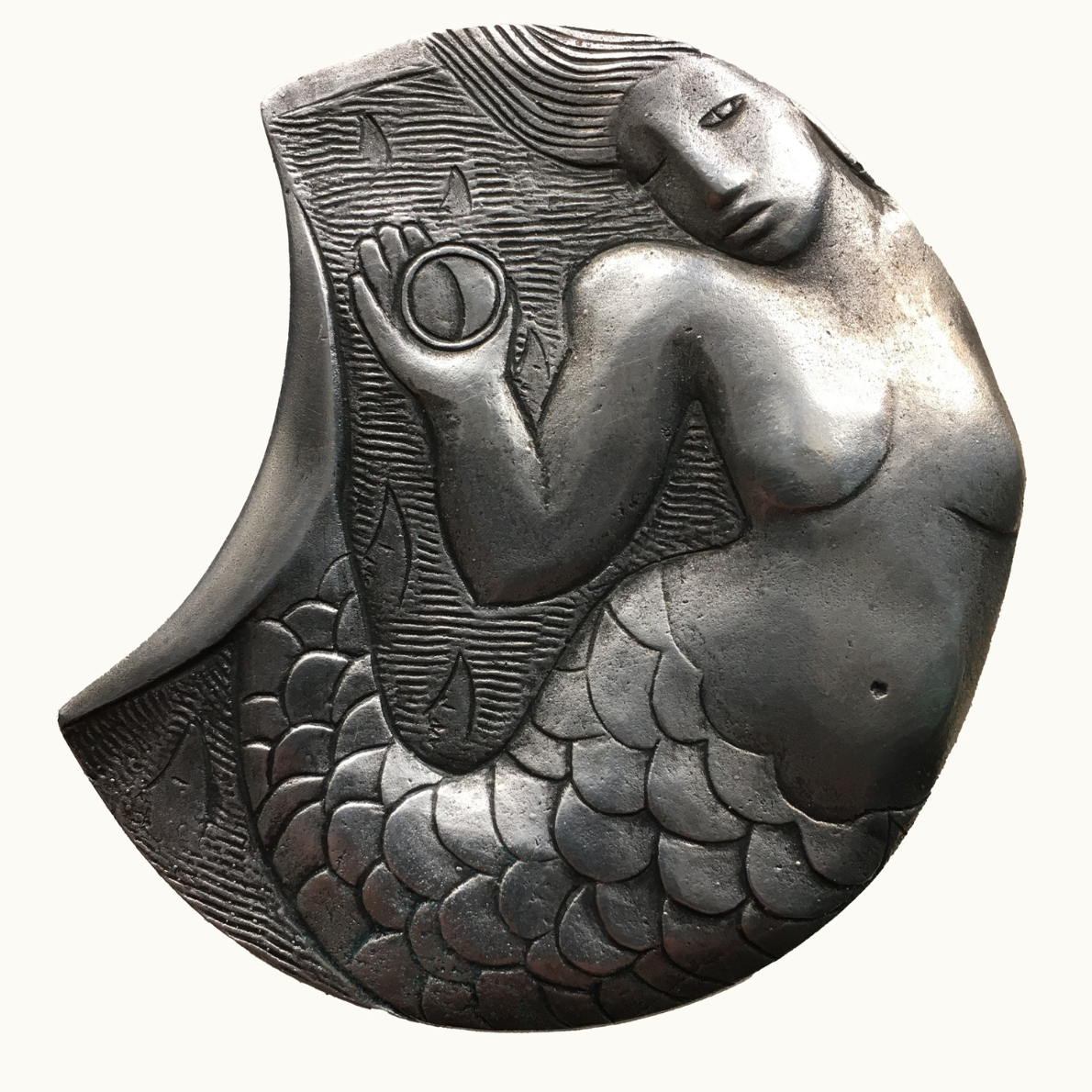 Decorative medal by Linda Crook of a mermaid with fish tail on a white background.