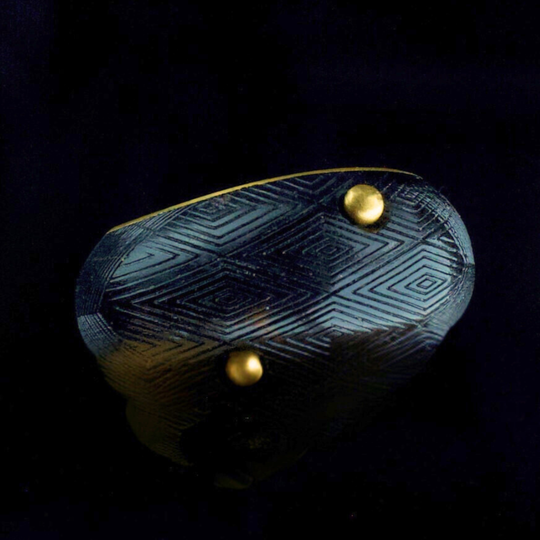 Decorative ring with geometric patterns and gold accents on a dark background by Makila Nsika